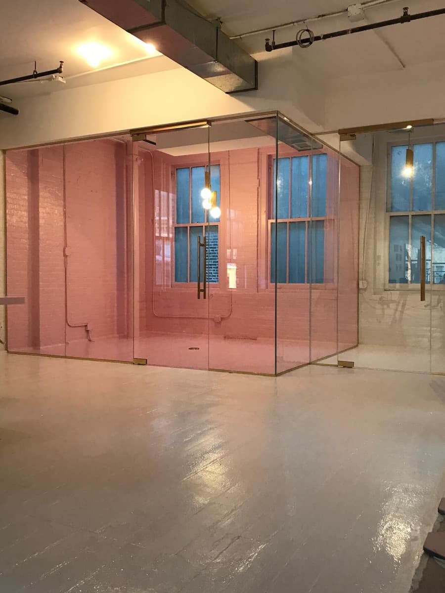 Glass-walled room with a pink wall and a freshly finished floor